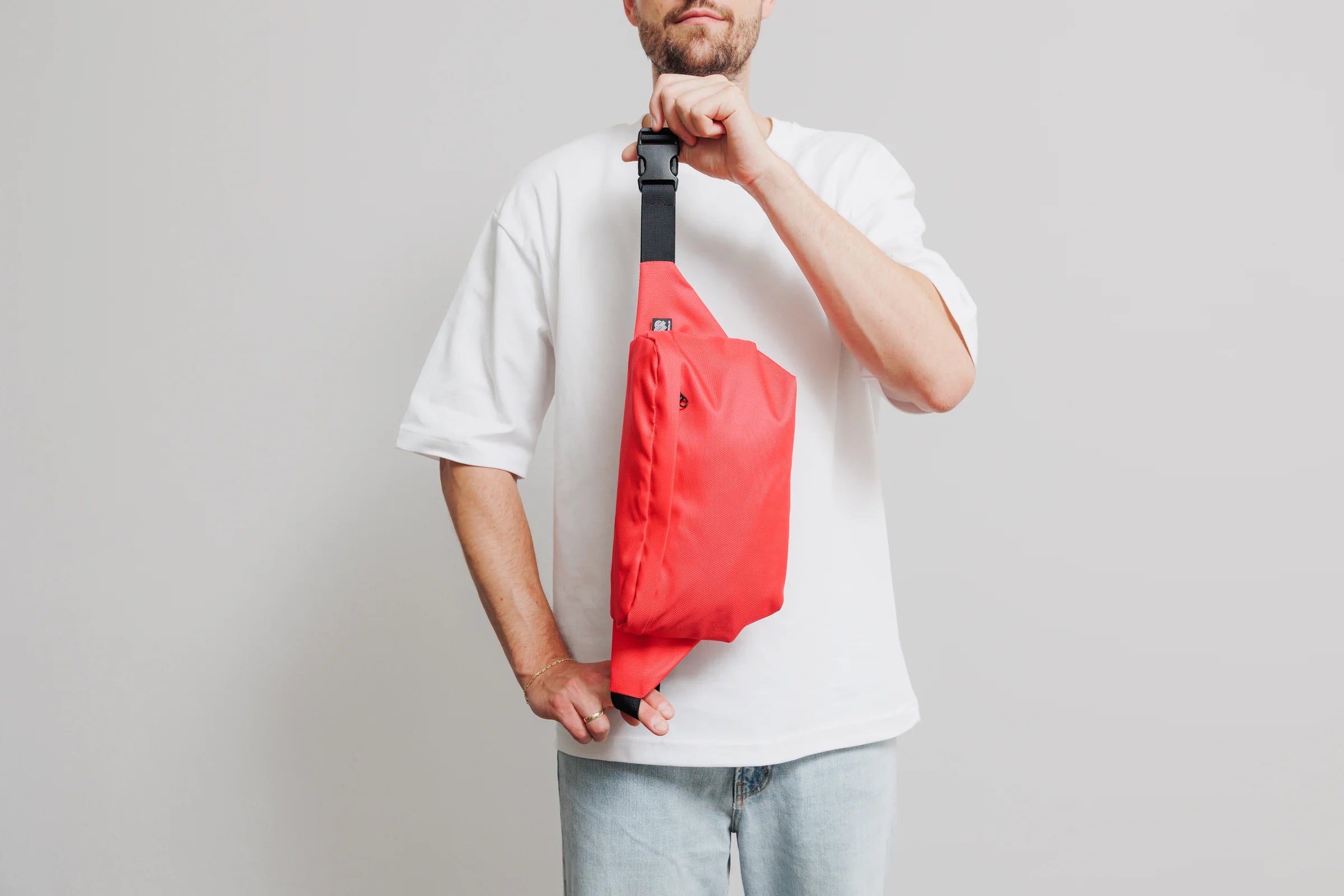 Große Bauchtasche aus Meeresplastik in Rot am Gurtband gehalten